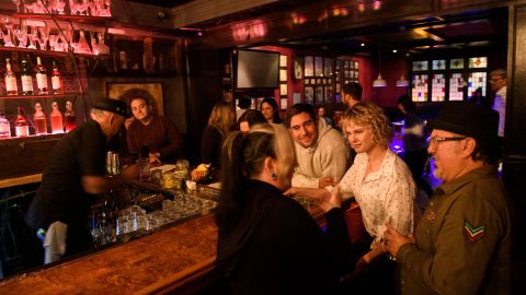 Fully vaccinated customers gather at the bar inside Risky Business, a private members-only club, that was once The Other Door but closed during the Covid-19 pandemic in the North Hollywood neighborhood of Los Angeles, California on May 21, 2021. - In order to go inside Risky Business, members must present their original vaccination card after being fully vaccinated, paying a small membership fee, signing a risk release form with penalties for lying, and waiting a full two weeks after competing their shots. While the policy is strict, once inside customers can enjoy an experience knowing that everyone else has been 100-percent vaccinated with an lively pre-pandemic atmosphere with people up close and personal - talking, hugging, playing pool and drinking without rules for masks or social distancing. (Photo by Patrick T. FALLON / AFP) (Photo by PATRICK T. FALLON/AFP via Getty Images)