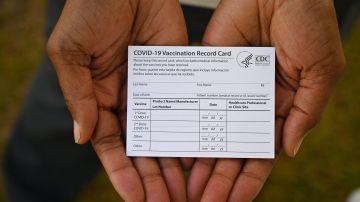 A healthcare worker displays a Covid-19 Vaccination Record Card during a vaccine and health clinic at QueensCare Health Center in a predominately Latino neighborhood in Los Angeles, California, August 11, 2021. - All teachers in California will have to be vaccinated against Covid-19 or submit to weekly virus tests, Governor Gavin Newsom announced on August 11, as authorities grapple with exploding infection rates. The number of people testing positive for the disease has surged in recent weeks, with the highly infectious Delta variant blamed for the bulk of new cases. (Photo by Robyn Beck / AFP) (Photo by ROBYN BECK/AFP via Getty Images)