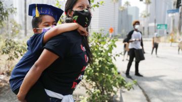 LOS ANGELES, CALIFORNIA - JUNE 23: A mother holds her daughter as Black Lives Matter-Los Angeles supporters protest outside the Unified School District headquarters calling on the board of education to defund school police on June 23, 2020 in Los Angeles, California. The demonstrators want the funds currently spent on campus police to be reallocated to other student-serving priorities. (Photo by Mario Tama/Getty Images)