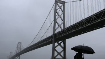 SAN FRANCISCO, CA - DECEMBER 11: A pedestrian walks in the rain next to the San Francisco-Oakland Bay Bridge on December 11, 2014 in San Francisco, California. The San Francisco Bay Area is being hit with a severe storm that is bringing high winds and heavy rain that have toppled trees and caused local flooding. (Photo by Justin Sullivan/Getty Images)