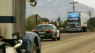 WRIGHTWOOD, CA - JULY 23: A wayward trucker (R) approaches a highway patrolman keeping watch at a roadblock as California Highway 138 is shut down to protect workers from road rage during a road-widening project on July 23, 2007 near Wrightwood, California, 50 miles northeast of Los Angeles. Before the closure, road workers received insults, death threats, BB gun shootings, and were the target of thrown objects from drivers angered by traffic delays during rush hour. The road is now shut down entirely until the project is finished, forcing 20,000 drivers per day into lengthy detours. (Photo by David McNew/Getty Images)
