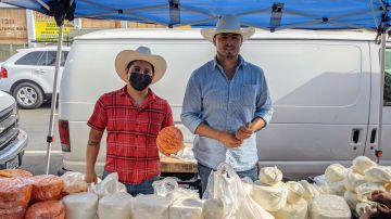 Iván Tapia y su primo Rafael Tapia vendiendo quesos en el distrito de las piñatas. (Jacqueline García/La Opinión)
