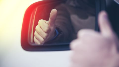 Foto de la mano de un conductor con el pulgar arriba