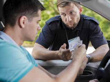 Foto de un oficial de policía solicitando identificación a un conductor