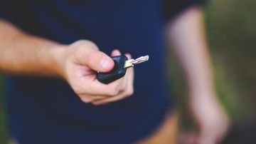 Foto de un hombre mostrando la llave de un auto en su mano derecha