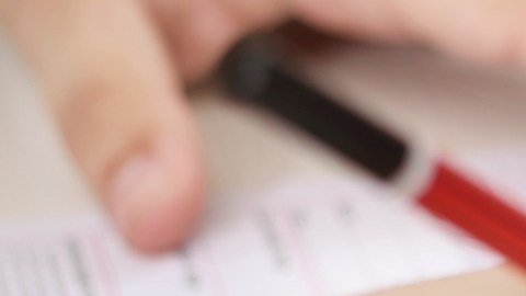 Foto de las manos de una persona presentando un examen escrito