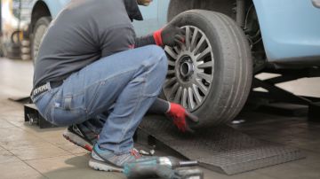 Foto de un hombre montando un neumático en un auto