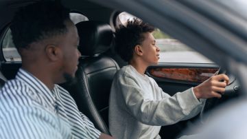 Foto de un adolescente aprendiendo a conducir con un adulto