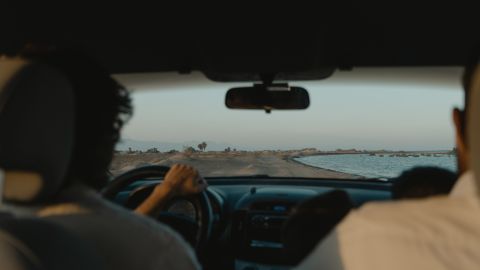 Foto de un conductor en compañía de un copiloto con una carretera al fondo