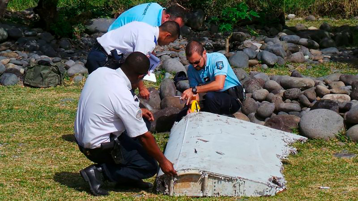 Oficiales de policía inspeccionan un resto del avión encontrado en la isla de La Reunión, en el Océano Índico.