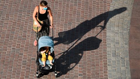 A woman wearing a protective mask pushes her baby in a stroller at Dubai Marina on May 5, 2020, after authorities of the United Arab Emirates started to ease a national lockdown put in place to curb the spread of the novel coronavirus. (Photo by Karim SAHIB / AFP) (Photo by KARIM SAHIB/AFP via Getty Images)