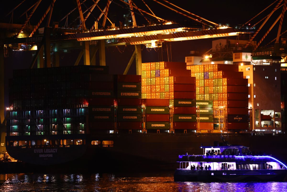 SAN PEDRO, CALIFORNIA - DECEMBER 04: Revelers ride past a container ship stacked with shipping containers at the Port of Los Angeles during the ‘Los Angeles Harbor Holiday Afloat Parade’ on December 4, 2021 in San Pedro, California. The 59th annual boat parade marking the start of the holiday season featured boats of various sizes competing for awards. A backlog of aging cargo at the ports of Los Angeles and Long Beach has decreased 37 percent since last month. (Photo by Mario Tama/Getty Images)