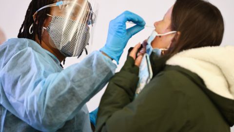 LOS ANGELES, CALIFORNIA - DECEMBER 21: Merline Jimenez (L) administers a COVID-19 nasopharyngeal swab to a person at a testing site located in the international terminal at Los Angeles International Airport (LAX) amid a surge in omicron variant cases on December 21, 2021 in Los Angeles, California. AAA estimates that over 109 million Americans will be traveling 50 miles or more during the holiday season between December 23 and January 2, an increase of 27.7% from 2020. (Photo by Mario Tama/Getty Images)