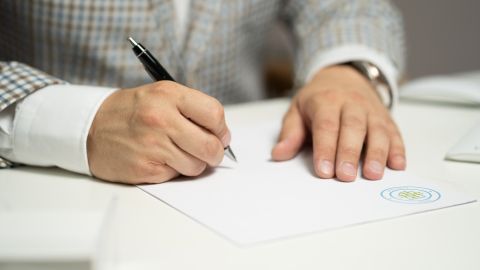 Foto de un hombre firmando varios documentos