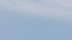 Foto de varios vehículos en un estacionamiento con una planta de Tesla al fondo