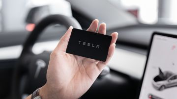 Foto de una persona en un vehículo Tesla mirando una tarjeta