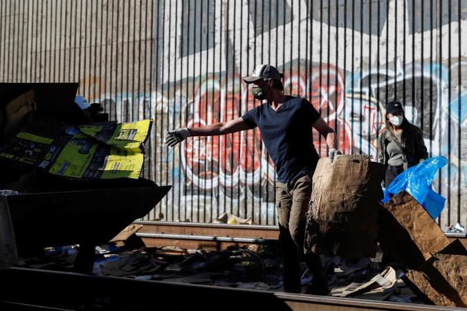 Los Angeles (United States), 20/01/2022.- California Governor Gavin Newsom (C) helps California Department of Transportation workers clean up destroyed boxes, packages, and debris, that line a section of the Union Pacific train tracks after being looted from cargo trains hauling Fed Ex, Amazon, UPS, and other box cars through the Lincoln Heights area in Los Angeles, California, USA, 20 January 2022. (Estados Unidos) EFE/EPA/CAROLINE BREHMAN