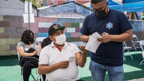 Isaí Pazo, director de la campaña de vacunación de CIELO (d) ayuda a un compatriota que se va a a vacunar contra Covid-19.