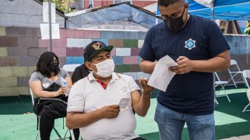 Isaí Pazo, director de la campaña de vacunación de CIELO (d) ayuda a un compatriota que se va a a vacunar contra Covid-19.