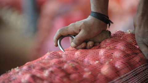 An Indian labourer prepares to carry onion bags towards waiting transport vehicles at a wholesale market yard in Hyderabad on August 17, 2013. India's food inflation rate rose to an annualized 9.5 percent led by a spike in onion prices which were up 34 percent from June. Onion prices have been rising in India as the crop has been hit by excessive rains. AFP PHOTO/Noah SEELAM (Photo credit should read NOAH SEELAM/AFP via Getty Images)