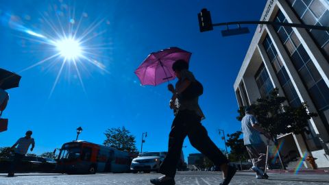 A pedestrian uses an umbrella on a hot sunny morning in Los Angeles October 24, 2017 amid a late season heatwave hitting southern California. Record temperatures in some locations including downtown Los Angeles reached 37 degrees Celsius (99 degrees Fahrenheit) before noon, tying a record set in 1909. / AFP PHOTO / FREDERIC J. BROWN (Photo credit should read FREDERIC J. BROWN/AFP via Getty Images)