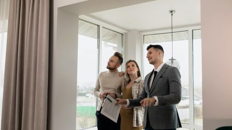 Foto de una pareja visitando una casa con un asesor inmobiliario