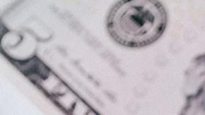 Foto de varios dólares con la palabra "taxes" sobre ellos