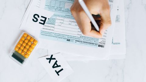 Foto de la mano de una persona escribiendo sobre formularios del IRS