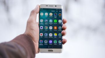 Foto de la mano de una persona sosteniendo un teléfono Samsung con la pantalla encendida