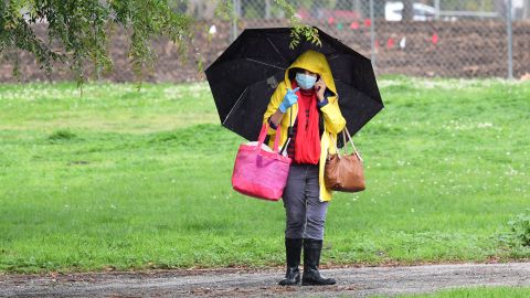 A woman walks in the rain with umbrella, facemask and gloves amid the coronavirus pandemic in Los Angeles, California on April 7, 2020, as Los Angeles County officials say the number of coronavirus cases has reached 6,910 with a death toll of 169. (Photo by Frederic J. BROWN / AFP) (Photo by FREDERIC J. BROWN/AFP via Getty Images)