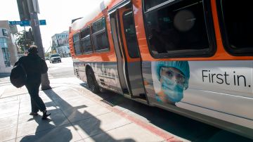A person gets off a bus with a photo of a health worker, amid the novel coronavirus pandemic, on May 15, 2020, on the Sunset Strip in West Hollywood, California. (Photo by VALERIE MACON / AFP) (Photo by VALERIE MACON/AFP via Getty Images)