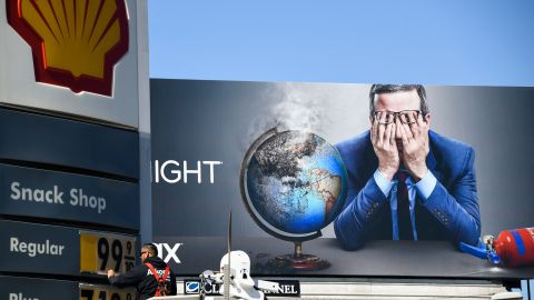 An electrical contractor repairs a sign with gasoline fuel prices above six and seven dollars a gallon at the Shell gas station at Fairfax and Olympic Blvd, near a billboard of John Oliver, in Los Angeles, California, on March 8, 2022. (Photo by Patrick T. FALLON / AFP) (Photo by PATRICK T. FALLON/AFP via Getty Images)