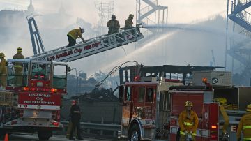 Firefighters douse the remains of a fire that destroyed an apartment complex that was under construction, in downtown Los Angeles, California, December 8, 2014. A pair of massive fires burst across the Los Angeles skyline early Monday, damaging four buildings and closing down freeways during the morning commute. No injuries were reported but the flames near a downtown freeway interchange could be seen for miles and billowing clouds of smoke closed down adjacent highways in two directions. City fire officials were unable to give an immediate cause for the blaze, which severely damaged a seven-story apartment building that was under construction. Damage to the structure appeared to be nearly total. Flames spread for a whole city block, nearly a million square feet, officials said. AFP PHOTO / ROBYN BECK (Photo credit should read ROBYN BECK/AFP via Getty Images)