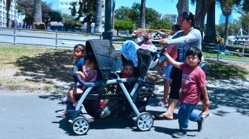 Babysitter Eusebia, from Guatemala, walks with children through MacArthur Park in the predominantly Hispanic/Latino neighborhood of Westlake in Los Angeles, California on June 19, 2018. - From cleaning ladies to construction workers to activists, members of LA's huge Latino community say they are horrified by the zero tolerance policy that has led to children being separated from their parents. (Photo by Frederic J. BROWN / AFP) / With AFP Story by Javier TOVAR: US-politics-immigration-children-trauma-health-research (Photo credit should read FREDERIC J. BROWN/AFP via Getty Images)