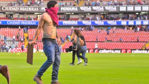 Un hincha camina en la cancha durante los disturbios en el Querétaro vs. Atlas.