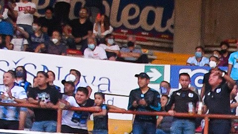 Aficionados de Querétaro saltándose una reja.