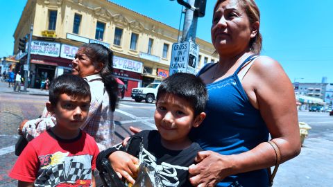 Maria and her boys Steven (L) and Brian (R) wait at an intersection near MacArthur Park in the predominantly Hispanic/Latino neighborhood of Westlake in Los Angeles, California on June 19, 2018. - From cleaning ladies to construction workers to activists, members of LA's huge Latino community say they are horrified by the zero tolerance policy that has led to children being separated from their parents. (Photo by Frederic J. BROWN / AFP) / With AFP Story by Javier TOVAR: US-politics-immigration-children-trauma-health-research (Photo credit should read FREDERIC J. BROWN/AFP via Getty Images)