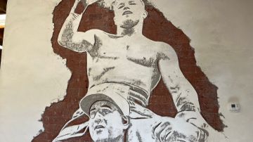 Canelo Álvarez en los hombros de Eddy Reynoso grabado en una pared de su gimnasio en San Diego.