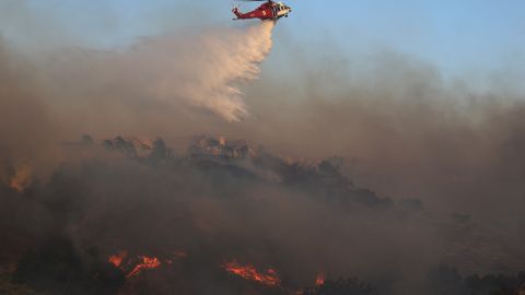 PORTER RANCH, CALIFORNIA - OCTOBER 11: A firefighting helicopter works the Saddleridge Fire on October 11, 2019 near Porter Ranch, California. The fast moving wind-driven fire has burned more than 7,500 acres and destroyed 25 structures. (Photo by Mario Tama/Getty Images)