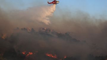 PORTER RANCH, CALIFORNIA - OCTOBER 11: A firefighting helicopter works the Saddleridge Fire on October 11, 2019 near Porter Ranch, California. The fast moving wind-driven fire has burned more than 7,500 acres and destroyed 25 structures. (Photo by Mario Tama/Getty Images)