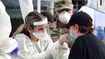A woman receives help with a nasal swab at a BusTest Express Covid-19 mobile testing site in Paramount, a city in Los Angeles County, California, on January 12, 2022. - California Governor Gavin Newsom visited the site earlier in the day and introduced his Covid-19 emergency response kit while speaking to the media. (Photo by Frederic J. BROWN / AFP) (Photo by FREDERIC J. BROWN/AFP via Getty Images)