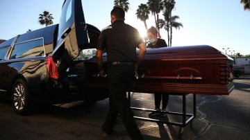 EL CAJON, CALIFORNIA - JANUARY 15: (EDITORIAL USE ONLY) Embalmer and funeral director Kristy Oliver (R) and funeral attendant Sam Deras load the casket of a person who died after contracting COVID-19 into a hearse at East County Mortuary on January 15, 2021 in El Cajon, California. The mortuary on average was handling about 50 decedents per month but owner Robert Zakar believes they may process closer to 100 in January as California continues to see a spike in coronavirus deaths. The mortuary holds the bodies of those who pass away due to COVID-19 for a minimum of three days before they are processed along with various other COVID-related safety measures. (Photo by Mario Tama/Getty Images)