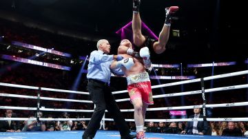Dmitry Bivol se cuelga de Saúl Álvarez en el round 11 de su pelea de campeonato mundial.