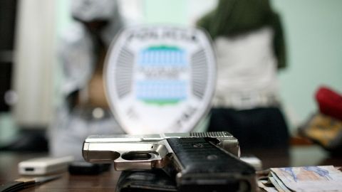 -- TO GO WITH AFP STORY IN SPANISH BY ALEXANDER MARTINEZ -- A handgun is seen on a police officer desk near two handcuffed 15-year old Venezuelan teenagers with their faces covered at a police station after being arrested for assault with a deadly weapon in the district of Sucre, Caracas on March 27, 2009. Crime, violence and insecurity are major issues in Venezuela, considered by NGO Venezuelan Violence Observatory to be the second most violent nation in Latin America - behind Colombia - after having registered 14,000 murders in 2008. AFP PHOTO/Thomas Coex (Photo credit should read THOMAS COEX/AFP via Getty Images)