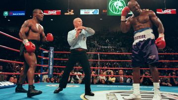 El árbitro Lane Mills detuvo la pelea en la tercera ronda mientras Evander Holyfield sostiene su oído, mientras Mike Tyson observa, el 28 de junio de 1997 durante su pelea por el campeonato de peso pesado de la WBA en el MGM Grand Garden Arena en Las Vegas, NV.