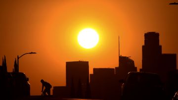 A cyclist rides across a street as the sun sets over Los Angeles, California on September 30, 2020. - A heat advisory is in effect through Friday in the Southern California region where temperatures are expected to climb into triple-digits, according to the National Weather Service. (Photo by Frederic J. BROWN / AFP) (Photo by FREDERIC J. BROWN/AFP via Getty Images)