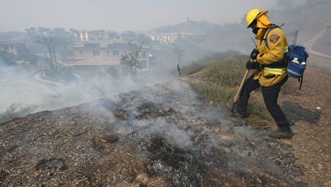 Orange County fire fighter John Nelson extinguishes hot spots about a residential community in the Silverado Fire October 26, 2020 in Irvine, California. - Some 60,000 people fled their homes near Los Angeles on October 26 as a fast-spreading wildfire raged across more than 7,200 acres (3,000 hectares), blocking key roadways and critically injuring two firefighters. The so-called Silverado Fire erupted early in the morning in the foothills of Irvine, about 37 miles (60 kilometers) southeast of Los Angeles, and quickly spread with no containment, fueled by dry conditions and erratic winds that prevented firefighting aircraft from flying. (Photo by Robyn Beck / AFP) (Photo by ROBYN BECK/AFP via Getty Images)