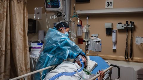 A health care worker tends to a Covid-19 patient while she is using a continuous positive airway pressure (CPAP) machine to help with her breathing difficulties in a Covid-19 holding pod at Providence St. Mary Medical Center in Apple Valley, California on January 11, 2021. - As Covid-19 tears through southern California, small hospitals in rural towns like Apple Valley have been overwhelmed, with coronavirus patients crammed into hallways, makeshift ICU beds and even the pediatric ward. When AFP visited St Mary hospital in this desert town of 70,000 people this week, palliative care supervisor Kari McGuire said her team were seeing "astronomical numbers of patients who are dying" from the novel coronavirus. (Photo by ARIANA DREHSLER / AFP) (Photo by ARIANA DREHSLER/AFP via Getty Images)