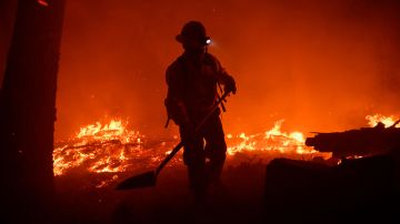 Kern County firefighter Roberto Figueroa wears a headlamp while working with a shovel as trees burn at night during the French Fire in the Sequoia National Forest near Wofford Heights, California on August 25, 2021. - The wildfire west of Lake Isabella in Kern County has burned over 20,000 acres while threatening homes in and around Wofford Heights and Kernville. (Photo by Patrick T. FALLON / AFP) (Photo by PATRICK T. FALLON/AFP via Getty Images)