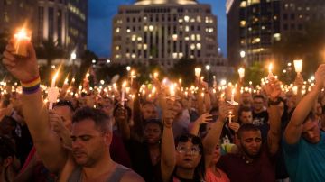 La gente sostiene velas durante un servicio conmemorativo vespertino para las víctimas de los tiroteos en el Pulse Nightclub, en el Dr. Phillips Center for the Performing Arts, el 13 de junio de 2016 en Orlando, Florida.